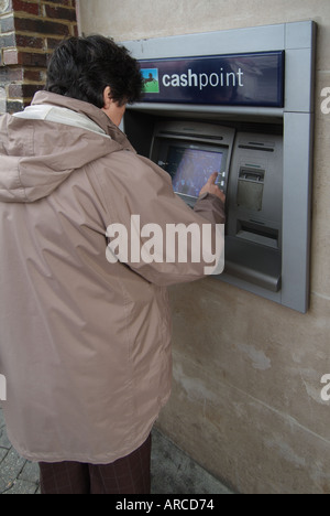 Housewife 62 sixtytwo sixty two year old age women using Lloyds TSB bank hole in wall cashpoint machine Stock Photo