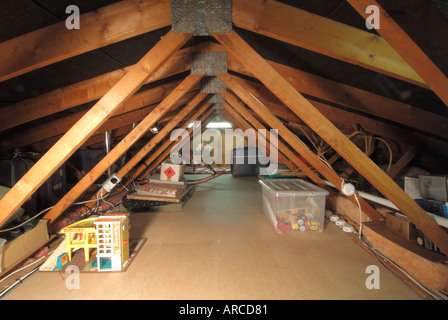 Domestic dwelling loft space low roof pitch showing timber roof trusses and mdf boarding to centre gangway for storage access Stock Photo