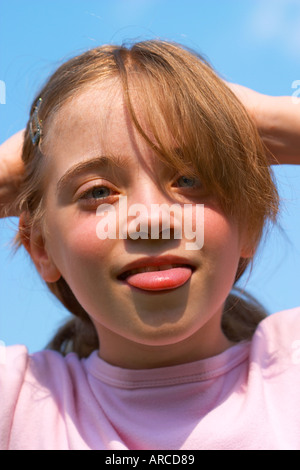 Young girl strikes a silly pose pulling face sticking out tongue  Stock Photo