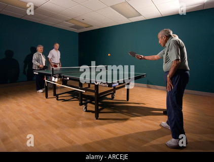 Senior men and women ranging in age from their 70 s to their 90 s play ping pong Stock Photo