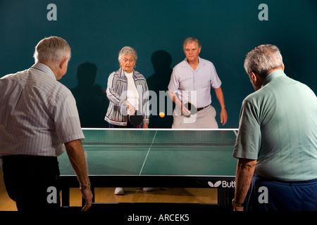 Senior men and women ranging in age from their 70 s to their 90 s play ping pong Stock Photo