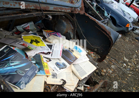 old car magazines sitting inside boot of rusty old car in scrap yard Stock Photo