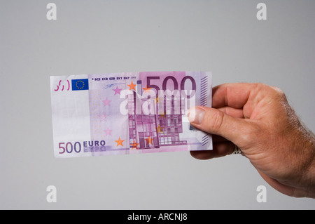 A male hand holding or offering a five hundred 500 euro banknote Stock Photo