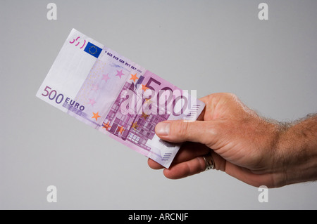 A male hand holding or offering a five hundred 500 euro banknote Stock Photo