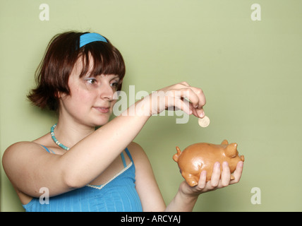 A girl inserting a coin in the piggy bank Stock Photo