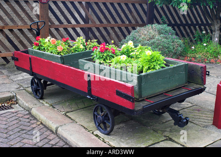 Railway trolley with flowers in boxes. Ingrow West Station. Keighley and Worth Valley Railway, Yorkshire, United Kingdom. Stock Photo