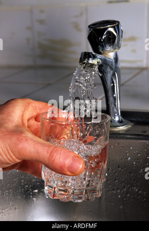 person filling glass with drinking water from tap Stock Photo