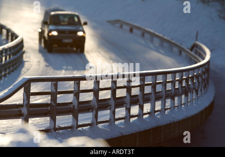 Metallic snowy road bridge railing and car driving on the icy road at Winter , Finland Stock Photo