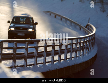 Metallic snowy road bridge railing and car driving on the road at Winter , Finland Stock Photo