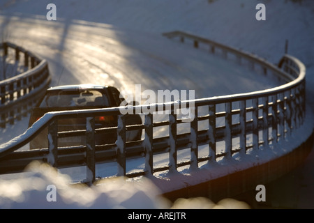 Metallic snowy road bridge railing and car driving on the road at Winter , Finland Stock Photo