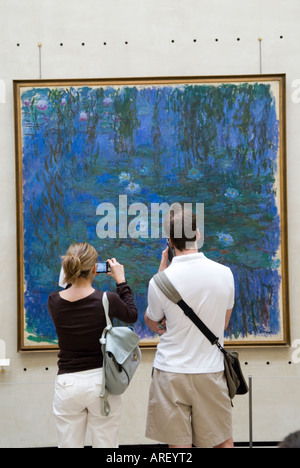 Visitors looking at Water Lilies an Impressionist painting by Claude Monet in the Musee d'Orsay Paris France Stock Photo