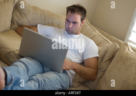 young man laying on sofa using laptop computer Stock Photo
