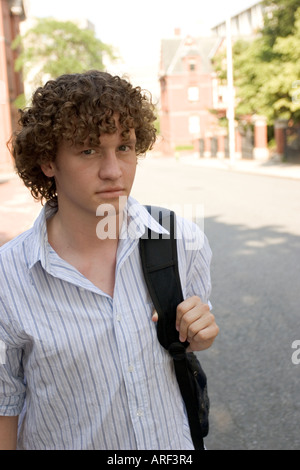Young man standing outdoors with backpack on shoulder Stock Photo