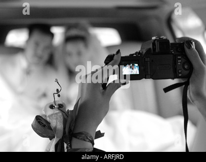 A newly married couple being videoed together in their wedding car Stock Photo