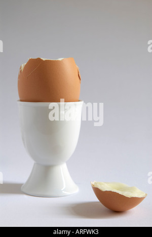 A boiled egg  with" top removed"  in an "white egg cup" Stock Photo