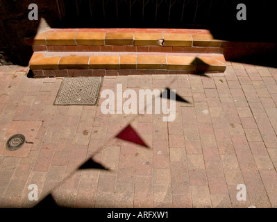 Colourful silhouettes of bunting flags projected onto a pavement and steps in Agde, southern france Stock Photo