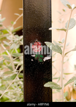 a close up of a tattoo of a red rose on a black metal post Stock Photo