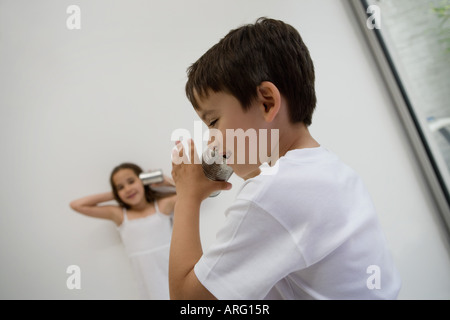 Girl and Boy using a tin can as a phone Stock Photo