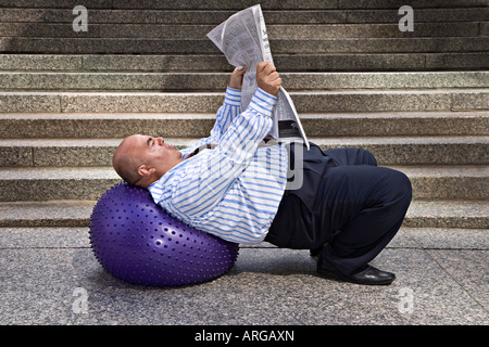 Businessman with Exercise Ball and Newspaper Stock Photo