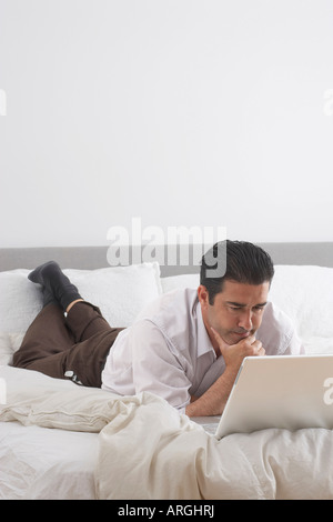 Man Using Laptop on Bed Stock Photo