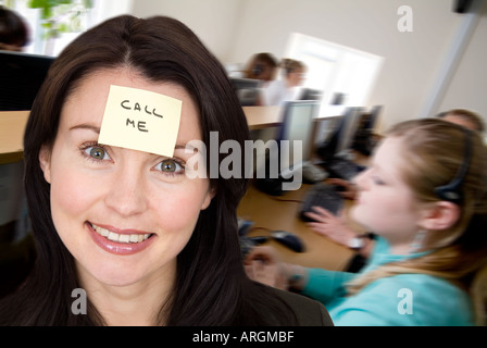 woman with sticky adhesive yellow note on her head with call me on it in a call centre Stock Photo