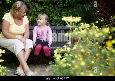 Grandmother and Granddaughter Sitting on Bench in Garden