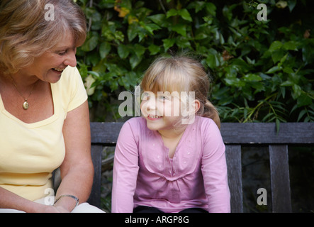 Grandmother and Granddaughter Sitting on Bench in Garden