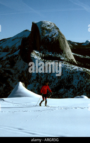 A cross-country skier makes his way past Half Dome in Yosemite National Park in California. Stock Photo