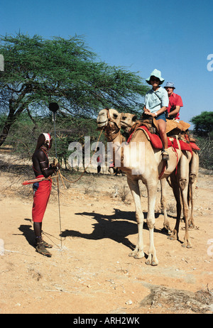 Two white Caucasian clients with their Samburu Guide or syce on a camel trekking safari in northern Kenya East Africa Stock Photo