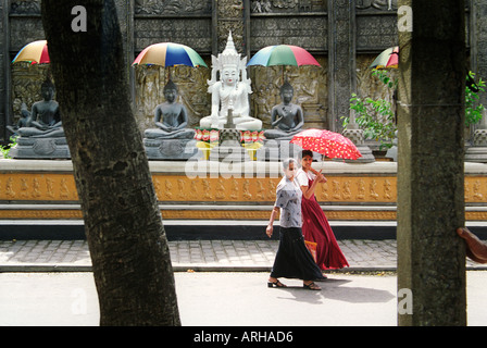 Women with an umbrella passing the Buddha images at the Gangarama Temple in Colombo Sri Lanka. Stock Photo