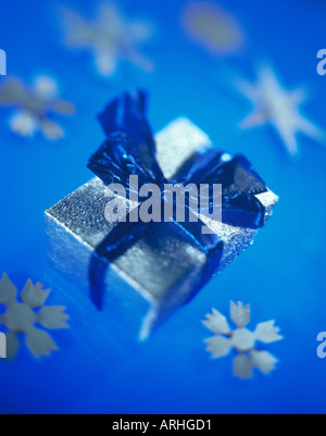 CHRISTMAS GIFT IN WRAPPING PAPER WITH SNOW FLAKE DECORATIONS Stock Photo