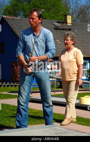 Elderly lady and young man playing golf on a mini golf course Stock Photo