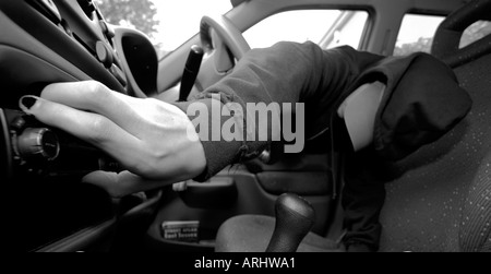 Staged photograph of a youth wearing a hoodie or hooded top taking a radio from a car PHOTOGRAPH AND TEXT 23RD OCTOBER 2005 Stock Photo