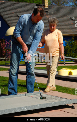 Elderly lady and young man playing golf on a mini golf course Stock Photo