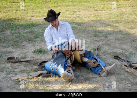 Cowboy practices holding onto his saddle prior to a bronc riding event at a Rodeo Stock Photo
