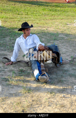 Cowboy practices holding onto his saddle prior to a bronc riding event at a Rodeo Stock Photo