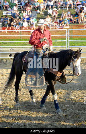 Cowboy participating in a rodeo event readies his rope for roping event Stock Photo