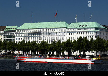 An excursion boat on the lake Binnenalster in front of the luxury hotel 'Raffles Vier Jahreszeiten' Four Seasons in the City of Stock Photo