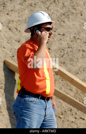 Construction worker talks on a cellular cell phone Stock Photo