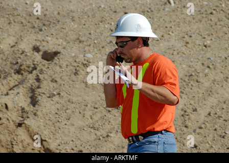 Construction worker talks on a cellular cell phone Stock Photo