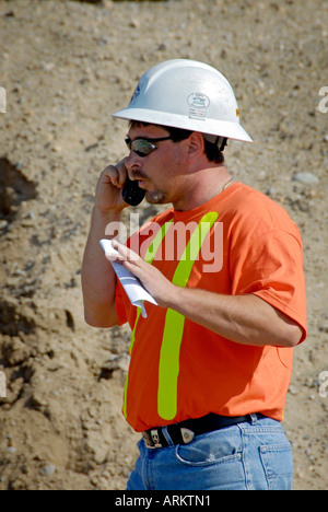 Construction worker talks on a cellular cell phone Stock Photo