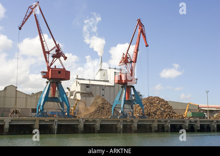 Cranes on quayside unloading scrap metal into trucks for reprocessing ...