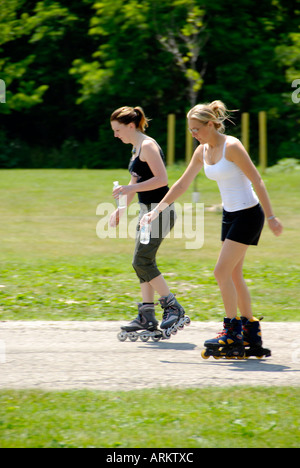 Two teen girls exercise on roller blades Stock Photo