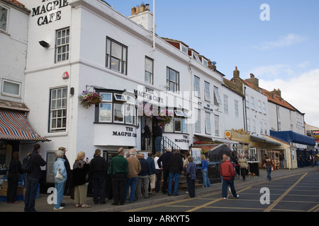 Queue of people outside 'Magpie Cafe' selling seafood and 'fish and chips' in historic building Whitby North Yorkshire England Stock Photo