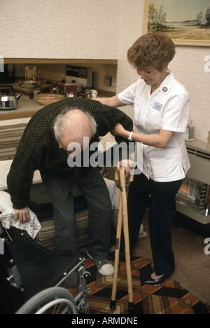 Health visitor assisting an old man with his canes Stock Photo