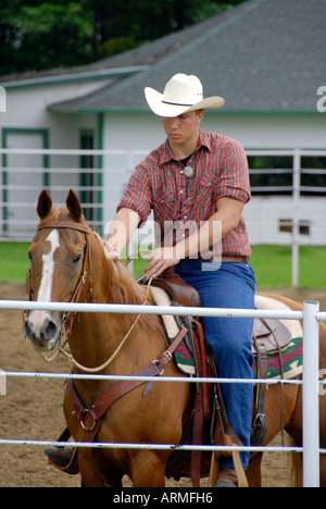 Male High school student riding a brown horse competes in equestrian event Stock Photo