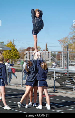 High School cheerleaders perform complicated and sometimes dangerous maneuvers during presentation at a football game Stock Photo