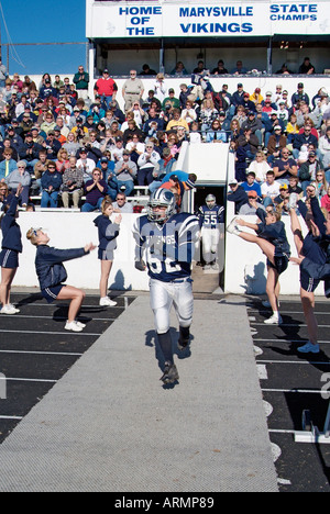 High school football players run onto the field during player introductions at a football game Stock Photo