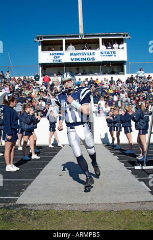 High school football players run onto the field during player introductions at a football game Stock Photo