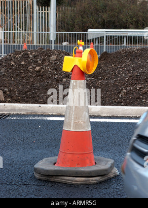 traffic cone with guide light on top at roadworks in new section of motorway with car passing belfast Northern Ireland UK Stock Photo